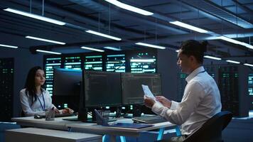 System administrator in data center maintaining accurate paperwork of hardware, generating reports. IT expert in high tech server farm doing workplace disaster recovery planning, camera B video
