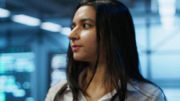 Engineer in high tech data center managing and maintaining databases, ensuring data integrity, security and availability. Indian woman updating server room supercomputers systems, camera A video