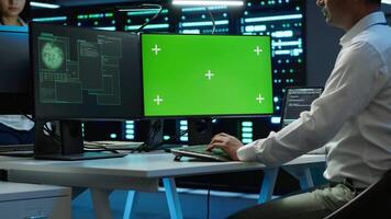 Engineer in server hub using green screen PC to stop hacker passing company firewall and stealing sensitive user data. Worker looking at mockup computer, seeing security breach notification, camera A video