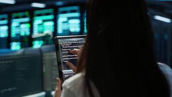 Data center software developer responsible for installation of networking equipment solving tasks on device. Close up of woman doing maintenance on server room infrastructure using tablet, camera A video