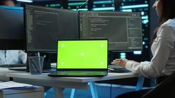 Data center engineer responsible for installation of networking equipment solving tasks on isolated screen laptop. Woman doing maintenance on server room infrastructure using mockup notebook, camera A video