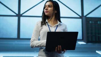 Admin in data center managing servers, operating systems and software programs. Tracking shot of woman in server hub ensuring networks are secure, up to date, and functioning properly, camera A video