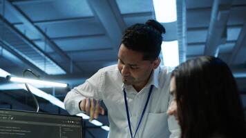 Teamworking colleagues in high tech data center managing and maintaining databases, ensuring data integrity, security and availability. Team of specialists updating server room systems, camera A video