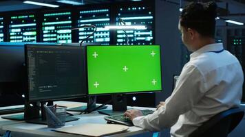 Programmer overseeing data center using isolated screen computer, ensuring system can handle networking tasks. IT expert in server room tracking network traffic with chroma key PC, camera A video