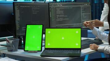 Engineer working with mockup laptop and tablet in data center used for managing gear energy consumption. Employee using green screen devices in workplace used for automation in server farm, camera A video