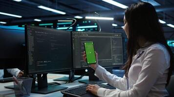 Worker overseeing data center using green screen mobile phone, ensuring system can handle networking tasks. IT expert in server room tracking network traffic with empty copy space smartphone, camera B video