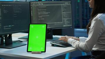 Software developer in data center monitoring security threats using mockup tablet. IT professional using green screen device, ensuring compliance with server room regulations, camera A video