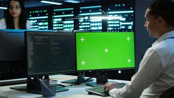 Programmer in data center managing and maintaining databases using mockup PC, ensuring data integrity and security. Expert updating server room systems using green screen computer, camera A video