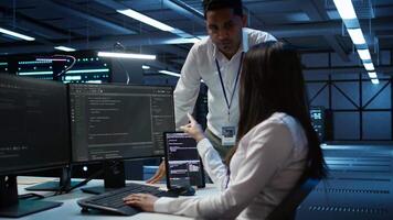 Engineering team colleagues in data center managing gear energy consumption, working on PC. Computer scientists using device in workspace used for automation in server room, camera B video