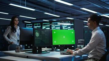 Engineer in server hub using green screen PC to stop hacker passing company firewall and stealing sensitive user data. Worker looking at mockup computer, seeing security breach notification, camera B video