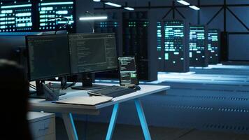 Person with paraplegia helped by coworker in data center to arrive at desk, coding on PC. Woman in wheelchair doing maintenance on server room infrastructure rackmounts, camera A video