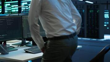 Engineer overseeing data center, making improvements and updates to ensure system can handle networking tasks, handheld camera shot. Indian man in server room tracking network traffic, camera A video
