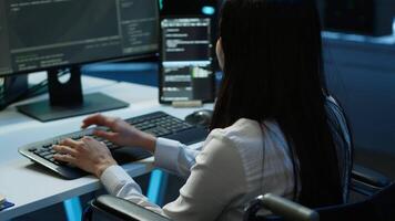Person with paraplegia working in inclusive server hub workspace, typing on PC. Woman in wheelchair doing tasks in data center housing advanced data storage infrastructure, camera A video