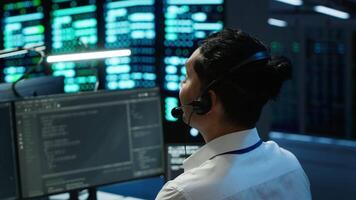 Data center computer scientist wearing mic headset, doing installation of networking equipment. Server hub IT professional talking in microphone with system administrators, camera A video