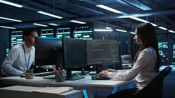 Management executive in data center ensuring system can handle networking tasks. Coworkers doing brainstorming in server room, tracking network traffic with PC, making improvements, camera B video