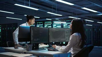 Team of researchers in data center monitoring security threats using PC, implementing cybersecurity measures. Teamworking colleagues ensuring compliance with regulations, camera B video