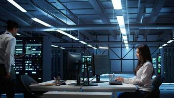 Admin in data center working with colleague to maintaining accurate documentation of equipment, generating reports. Server hub teamworking coworkers doing disaster recovery planning, camera B video