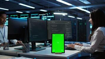 Software developer in data center monitoring security threats using mockup tablet. IT professional using green screen device, ensuring compliance with server room regulations, camera B video