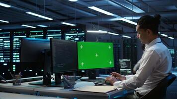 System administrator overseeing data center using green screen computer, ensuring system can handle networking tasks. IT expert in server room tracking network traffic with mockup PC, camera B video