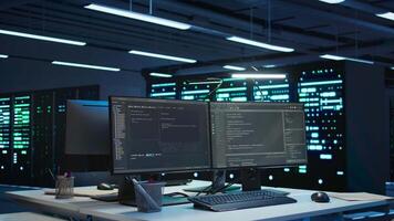 High tech data center with networking systems installed used for managing hardware. Code running on computer screens in technologically advanced server hub used for overseeing equipment, panning shot video