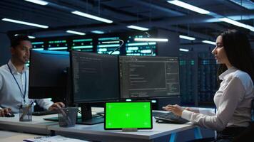 Data center developer responsible for installation of networking equipment solving tasks on green screen device. Woman doing maintenance on server room infrastructure using chroma key tablet, camera B video