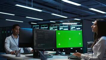 System administrator in data center installing software on green screen computer, troubleshooting issues. IT expert uses mockup PC in server hub, establishing performance benchmarks, camera B video