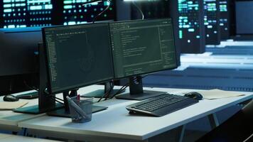 Data center workspace with networking systems installed used for managing supercomputers. Computer displays on desk in high tech server farm used for overseeing equipment video