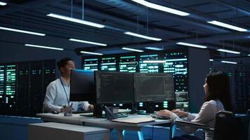 Person with paraplegia working in inclusive server hub workspace, typing on PC. Woman in wheelchair doing tasks in data center housing advanced data storage infrastructure, camera B video