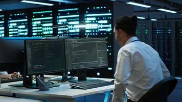Engineer in data center installing software on computer, troubleshooting issues, handheld camera shot. IT professional in server hub establishing performance benchmarks, camera A video