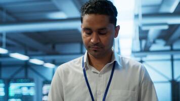 System administrator in data center managing and maintaining databases, ensuring data integrity, security and availability. IT worker updating server room supercomputers systems, camera A video