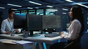 Team of technicians in data center designing, implementing and managing infrastructure to ensure optimal performance and reliability. Teamworking colleagues in server room coding on computer, camera B video