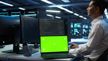 Admin in data center using isolated screen laptop to design, implement and manage gear, ensuring optimal performance and reliability. Expert in server room coding on chroma key notebook, camera B video