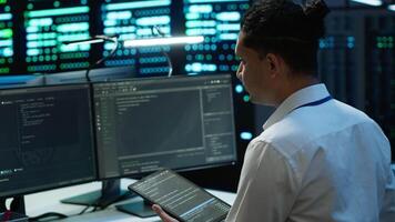System administrator in data center installing software on computer, troubleshooting issues using tablet. IT staff member in server hub establishing performance benchmarks, camera A video