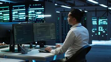 Developer and coworker overseeing data center, making improvements and updates to ensure system can handle networking tasks. Teamworking colleagues in server room tracking network traffic, camera A video