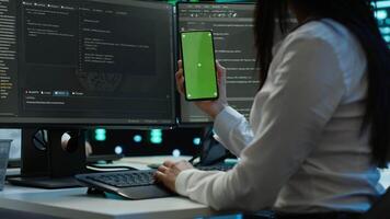 Worker overseeing data center using green screen mobile phone, ensuring system can handle networking tasks. IT expert in server room tracking network traffic with empty copy space smartphone, camera A video