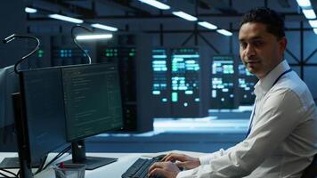 Portrait of upbeat admin in data center managing servers, operating systems and software programs. Joyous specialist in server hub ensuring networks are secure and functioning properly, camera A video