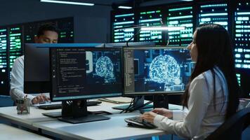 Team of engineers using AI tech on computer to do checkup in server room. Data center workers using artificial intelligence technology to process datasets for training, camera A video