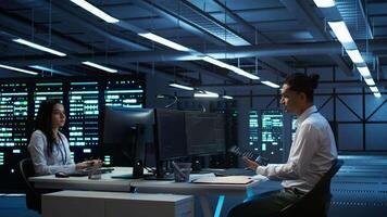 System administrator in data center installing software on computer, troubleshooting issues using tablet. IT staff member in server hub establishing performance benchmarks, camera B video