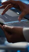 Vertical Programmer using device in data center, managing servers, operating systems. Close up of specialist in server hub using tablet to ensure networks are secure and functioning properly, camera B video