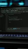 Vertical Focus on laptop used by engineers coding in modern data center, monitoring security threats. Close up of notebook used by employee in blurry background ensuring compliance with regulations, camera A video
