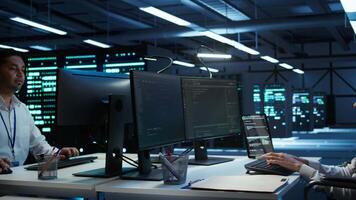 System administrator in wheelchair overseeing data center using computer, ensuring system can handle networking tasks. Person with paraplegia in server room tracking network traffic with PC video