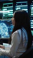 Vertical Team of engineers using AI tech on computer to do checkup in server room. Data center workers using artificial intelligence technology to process datasets for training, camera A video