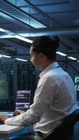 Vertical Team of technicians in server hub alerted by hacker passing firewall and stealing sensitive data. Coworkers panicking after seeing security breach notification on PC in data center workspace, camera B video