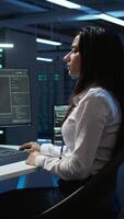 Vertical Team of technicians in data center designing, implementing and managing infrastructure to ensure optimal performance and reliability. Teamworking colleagues in server room coding on computer, camera B video