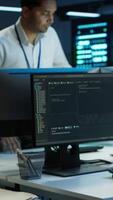 Vertical Computer scientists in data center managing and maintaining databases, ensuring data integrity and security. IT staff members updating server room systems using, camera A video