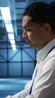Vertical Portrait of smiling data center technician responsible for installation and repair of networking equipment solving tasks. Jolly IT expert doing maintenance on server room infrastructure, camera B video