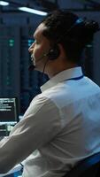 Vertical Data center agent providing logistics support to businesses and overseeing infrastructure. Server farm worker oversees hardware rackmounts and communicates with technicians, camera A video