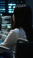 Vertical Person with paraplegia in inclusive server hub overseeing data center, making improvements. Woman in wheelchair doing tasks in data center, tracking network traffic, camera A video