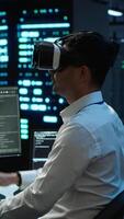 Vertical Data center admin responsible for installation of networking systems wearing high tech VR headset. IT worker doing maintenance on server farm gear using virtual reality technology, camera A video