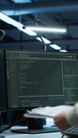 Vertical Engineer in data center installing software on computer, helping maintain network, troubleshooting arising issues. IT expert in server room establishing performance benchmarks, camera A video